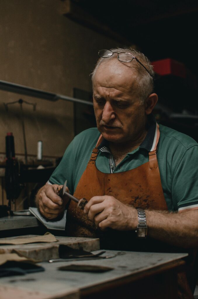 Portrait of a senior artisan crafting in his workshop with focused precision.