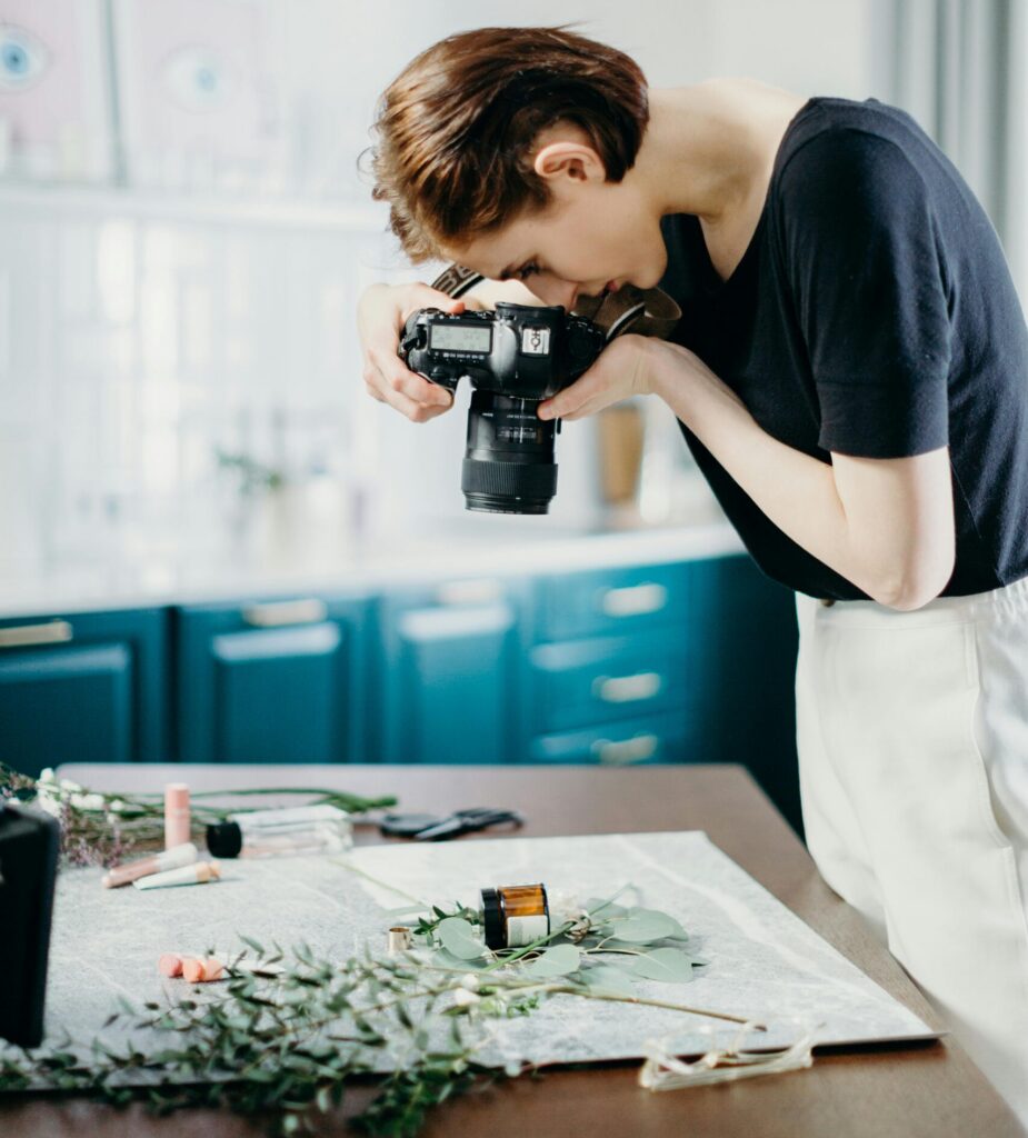 Woman taking photos of a still life setup with camera in a modern indoor setting.