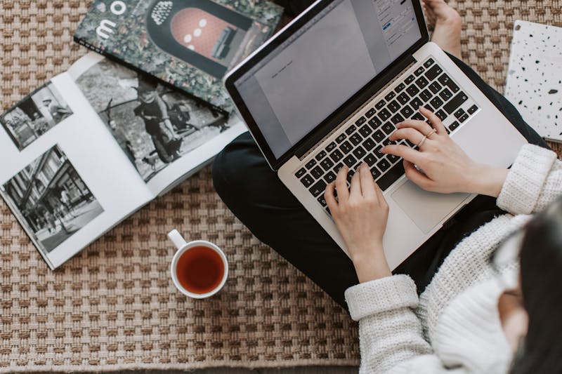 Création de site internet – Femme utilisant un ordinateur et lisant un journal en ligne